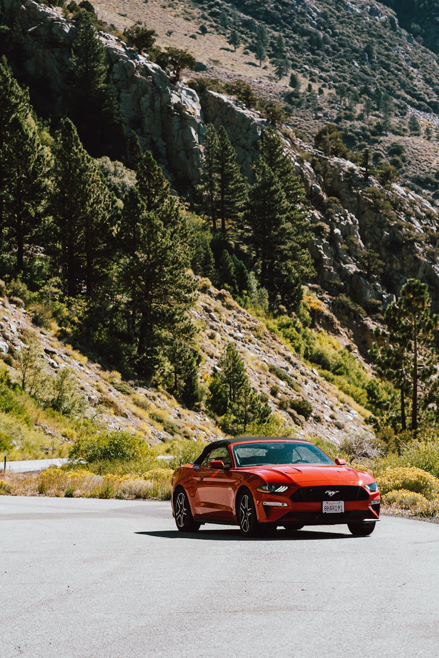 An orange sports car driving on a mountain road.