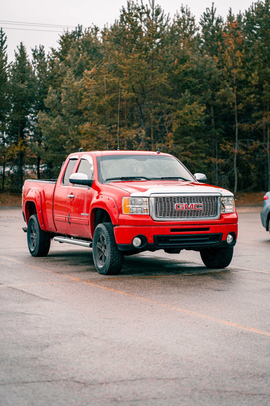 A red pickup truck parked on wet pavement.