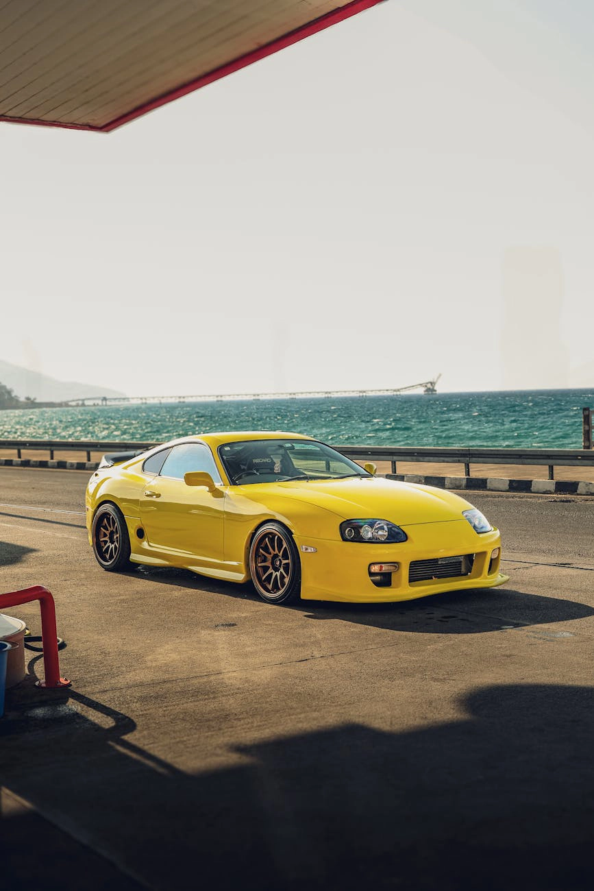 A yellow sports car parked in front of a bright building.