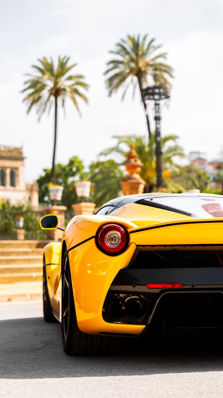 Yellow sports car parked near palm trees